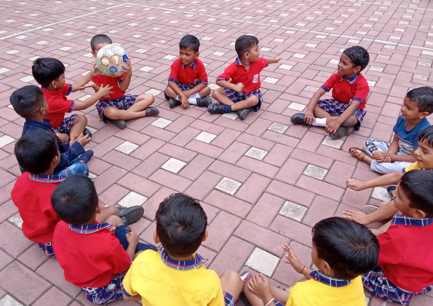 Kindergarten boys sitting in a circle playing ball passing game